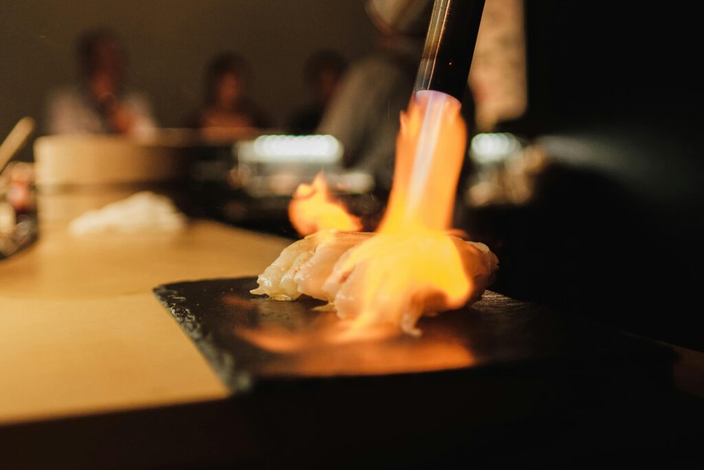 A sushi chef, demonstrating a unique style of preparing sushi with a blow torch. 