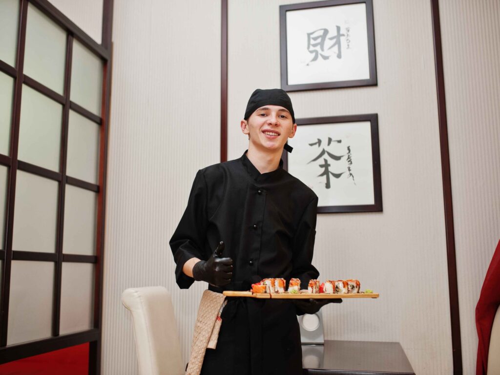 A sushi chef holding a platter of the dish, showcasing the craft has transcended borders.