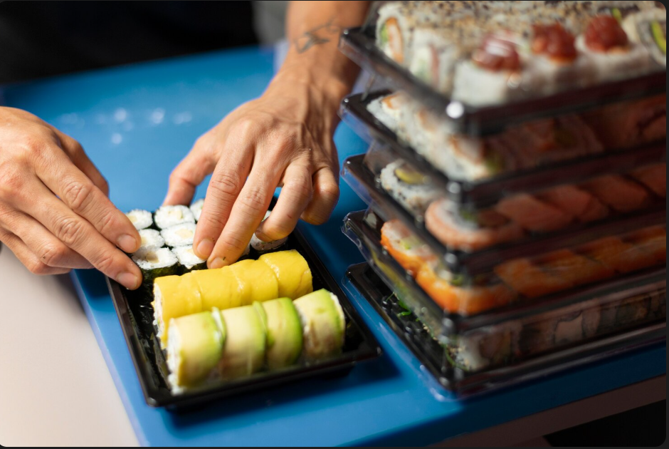 A chef carefully packing a tray of sushi.