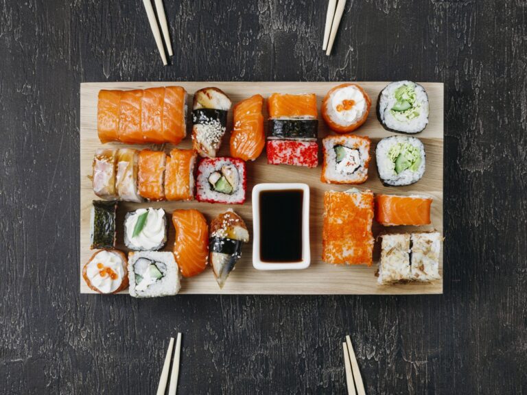 A variety of different sushi neatly displayed on a wooden tray.