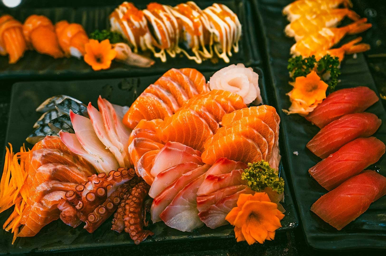Japanese sushi and sashimi platter with salmon, tuna, shrimp nigiri, octopus, mackerel, and roe-topped rolls, highlighting freshness and presentation.