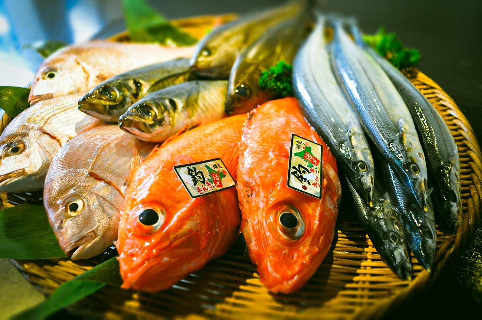 Assorted fish arranged on a woven bamboo tray, ready for sushi and sashimi preparation.