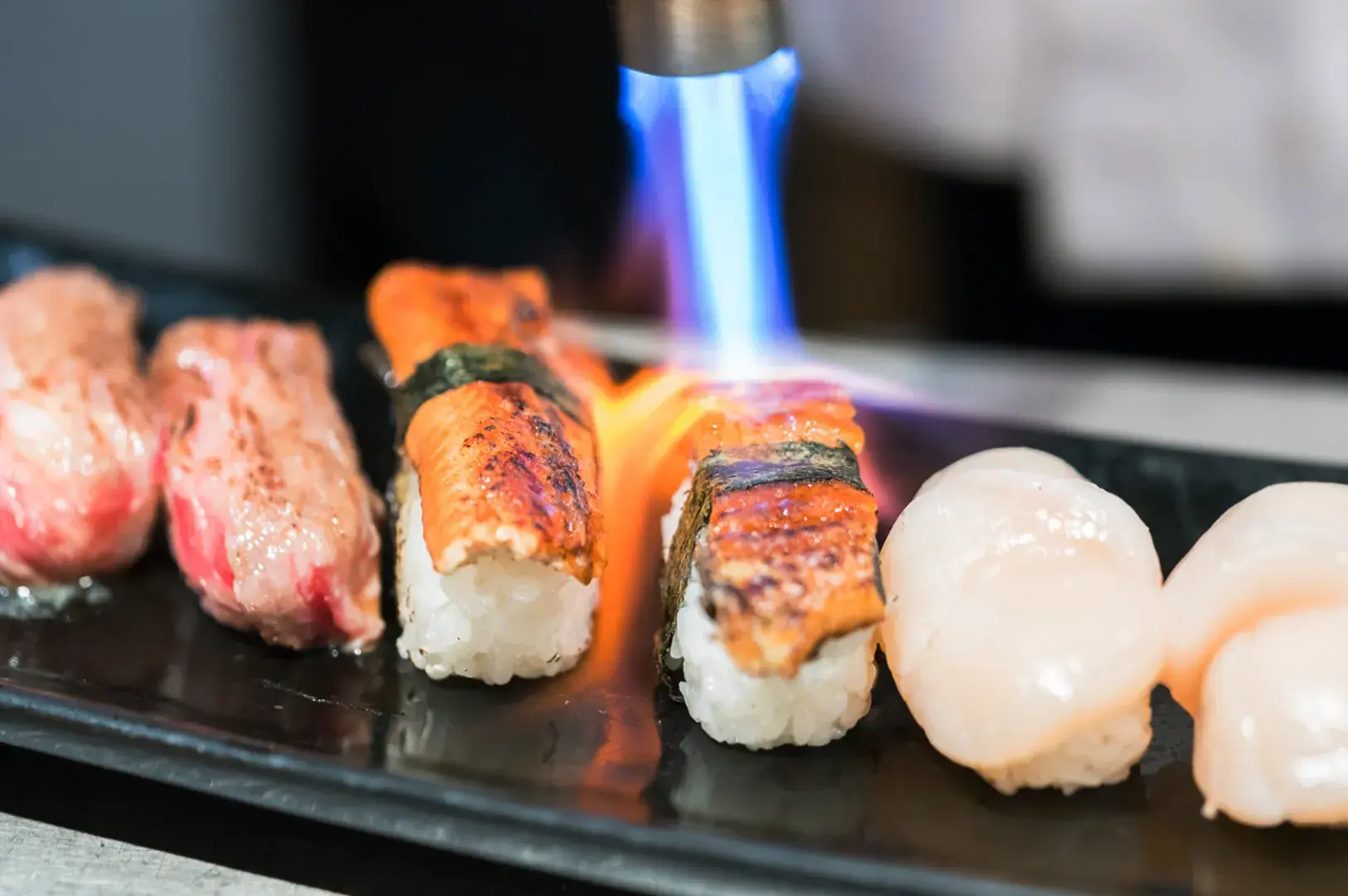 Sushi chef using blowtorch to sear aburi nigiri