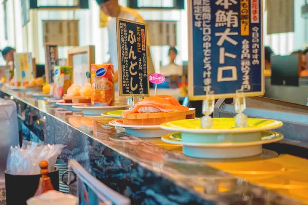 Sushi plates circulating on a conveyor belt inside a Japanese sushi restaurant.