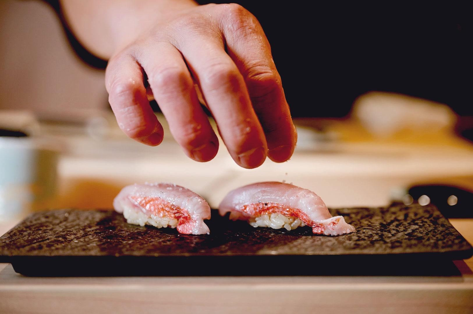 Close-up of chef seasoning fresh nigiri sushi with precision Singapore