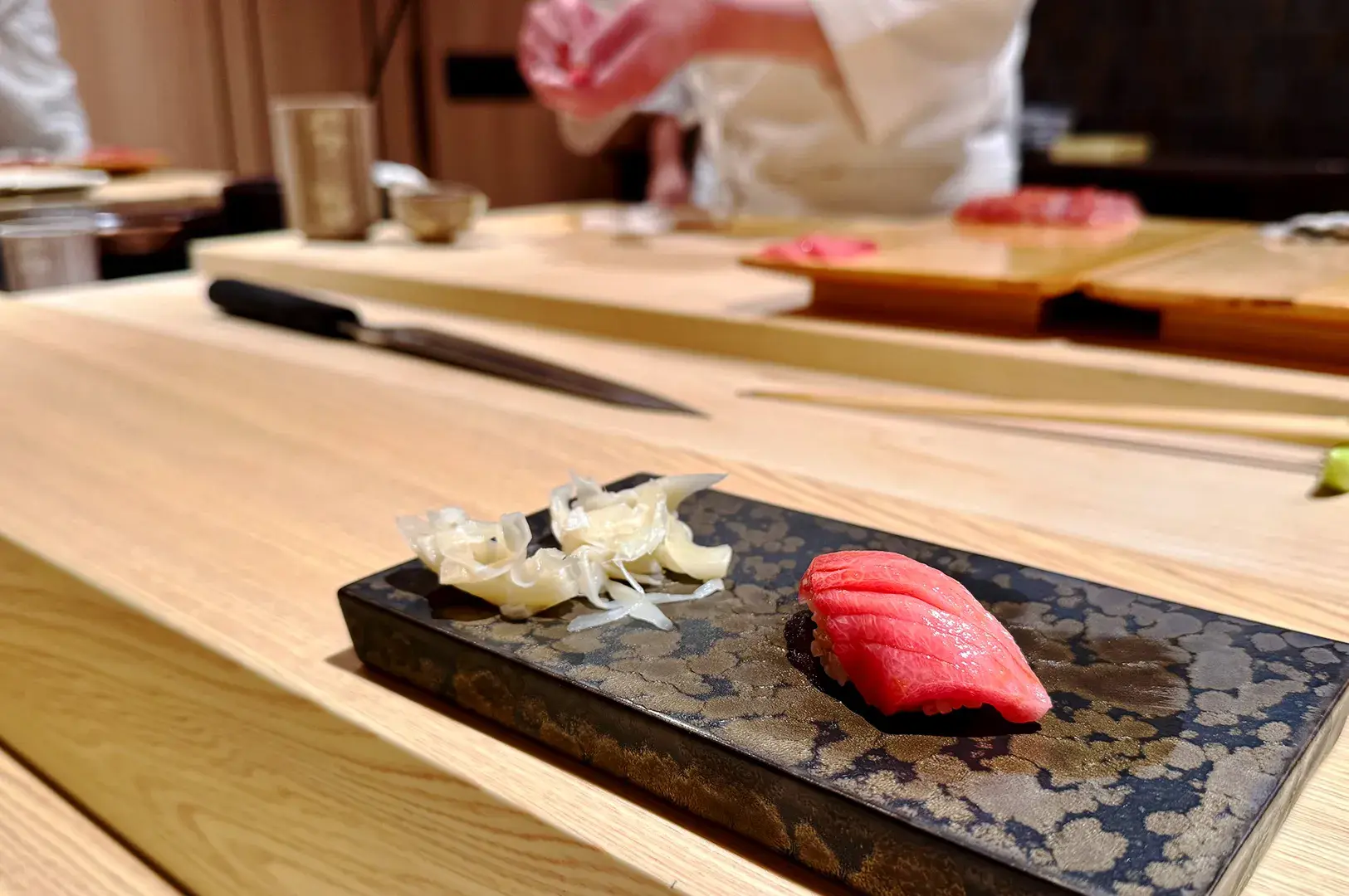 Nigiri sushi served at an omakase counter with chef in background