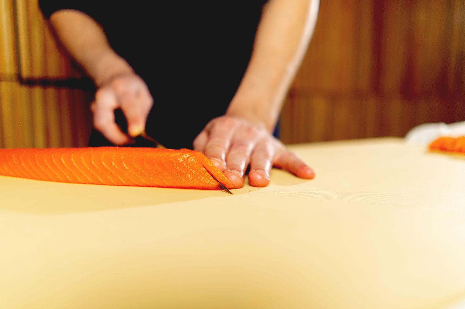 Chef slicing salmon sashimi with a sharp knife