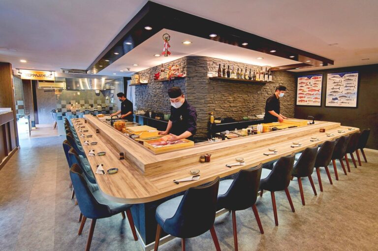 Chef preparing sushi at omakase counter in Singapore sushi restaurant.