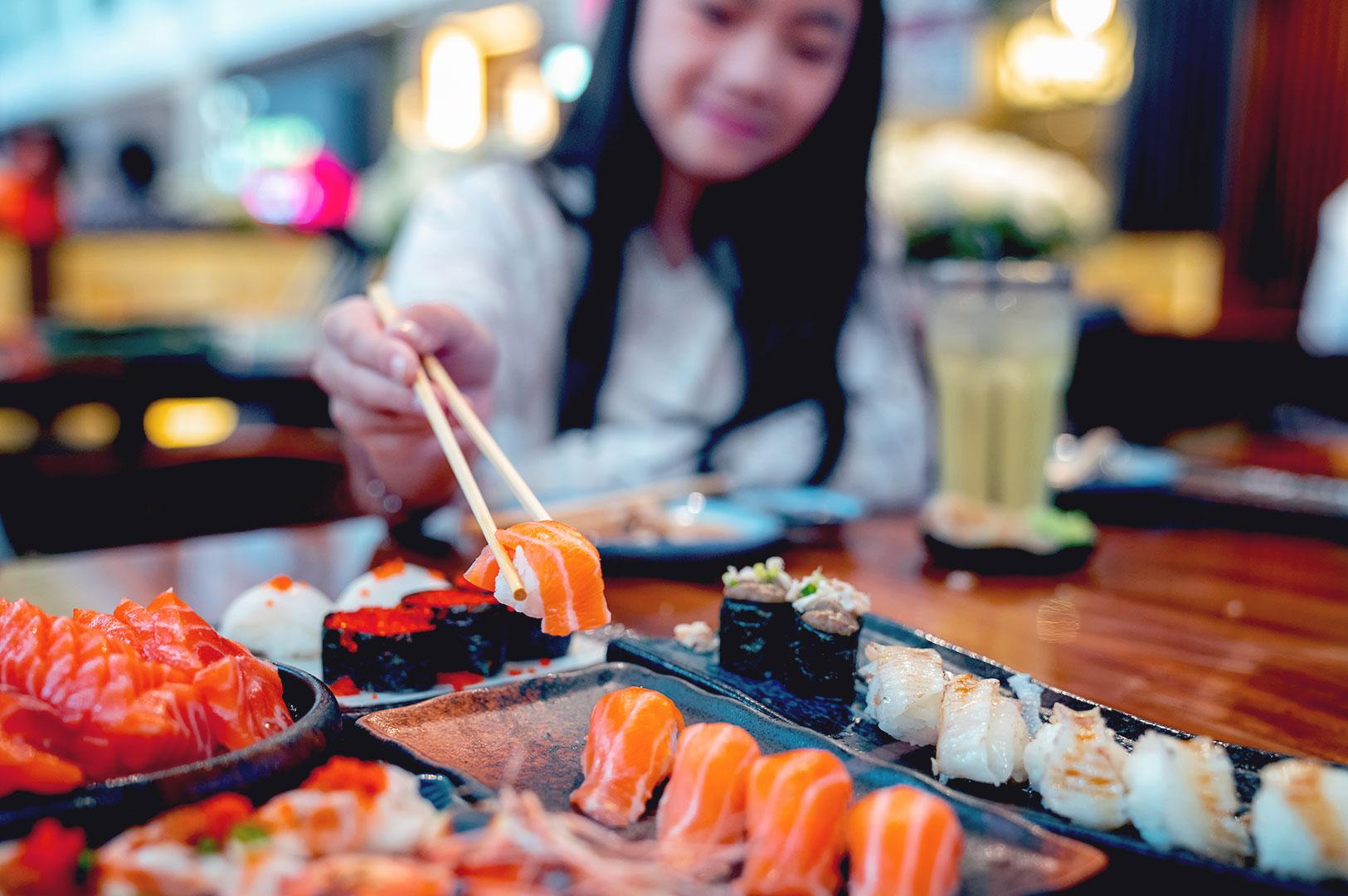 Woman enjoying sushi and sashimi dining experience at affordable Japanese restaurant Singapore