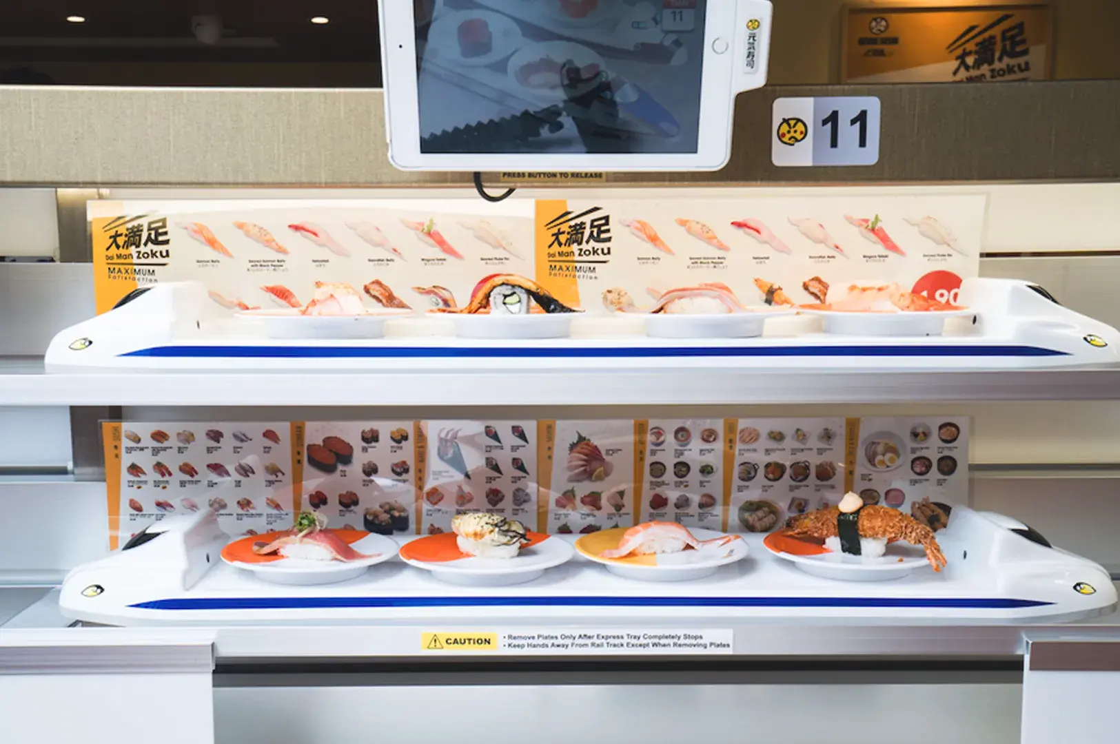 Genki Sushi Singapore train delivery system serving fresh sushi directly to the table in a modern Japanese dining environment