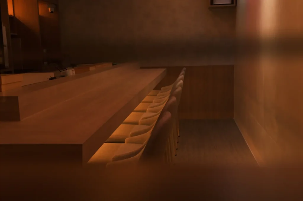 Sushi omakase counter with warm lighting.