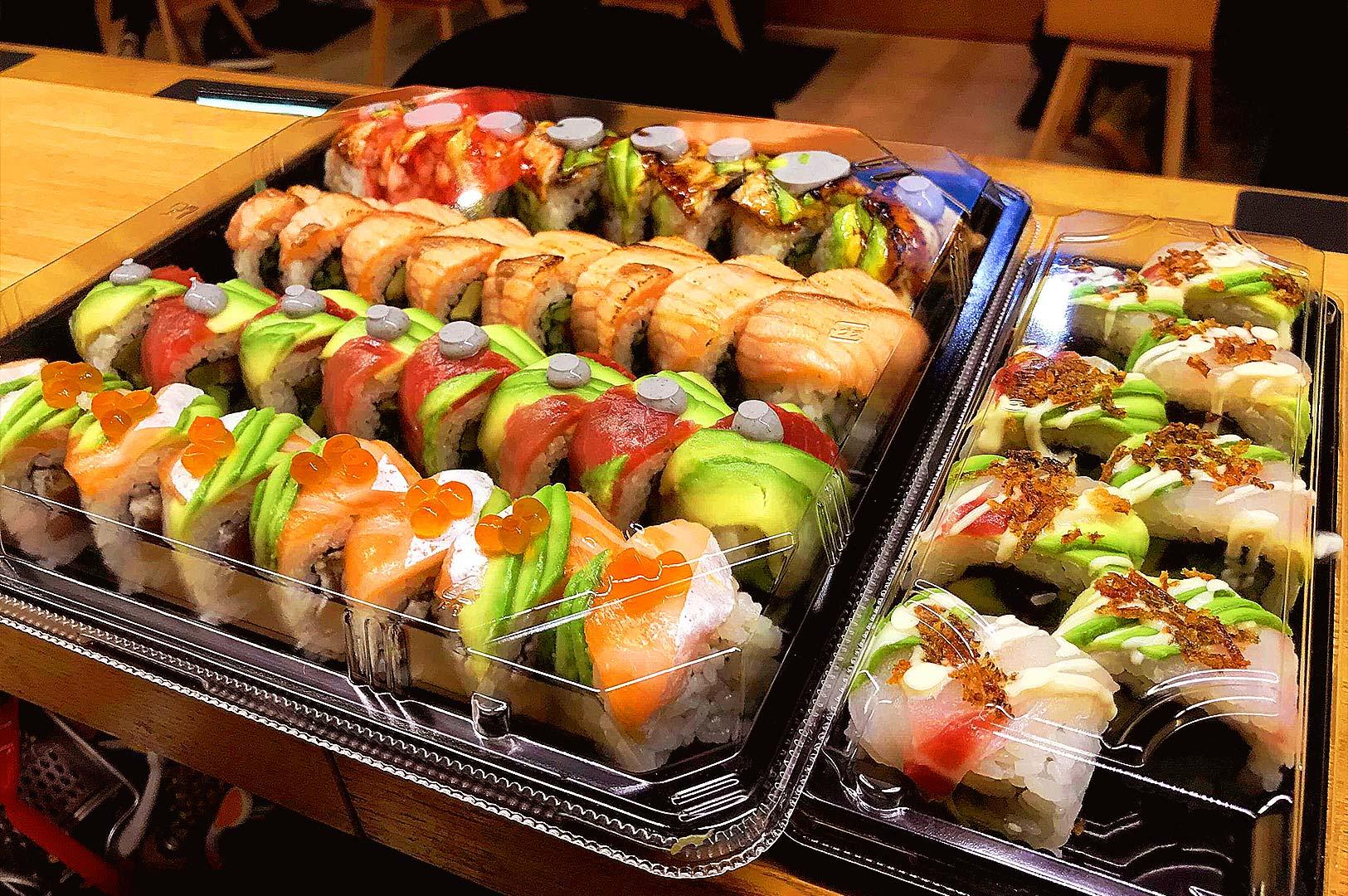 Affordable sushi platter in Singapore featuring salmon, tuna, and avocado rolls in takeaway packaging, highlighting casual Japanese dining and sushi delivery culture