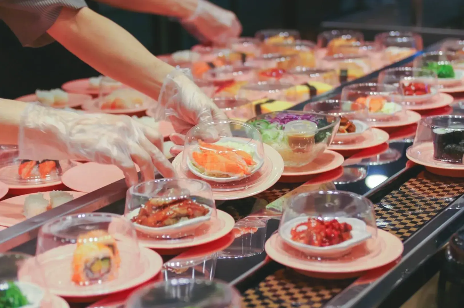 Busy Sushi Express Singapore outlet with affordable sushi plates circulating on a conveyor belt and diners enjoying quick meals