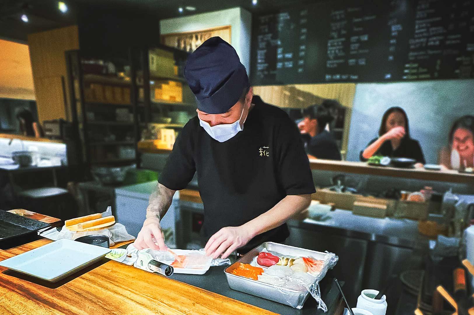 Sushi chef preparing fresh nigiri at a casual Japanese restaurant in Singapore, showcasing affordable sushi craftsmanship and quality ingredients