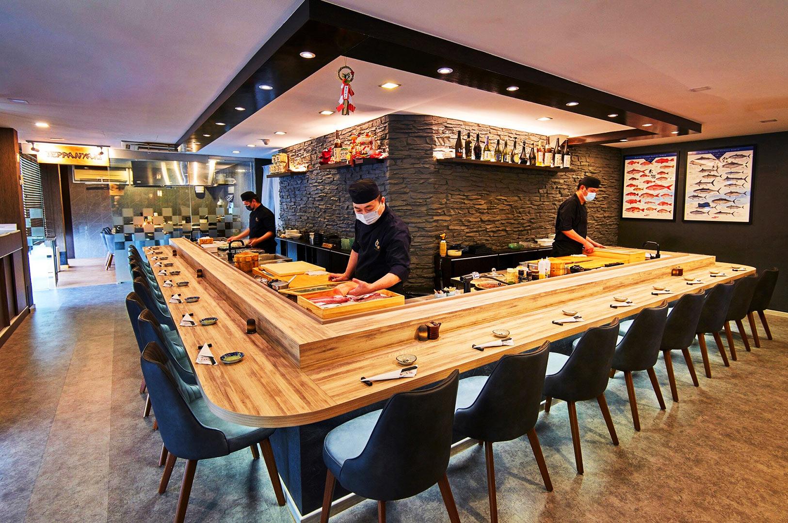 Japanese sushi bar in Singapore with chefs preparing fresh seafood at a counter, representing affordable omakase and high-quality sushi dining experience