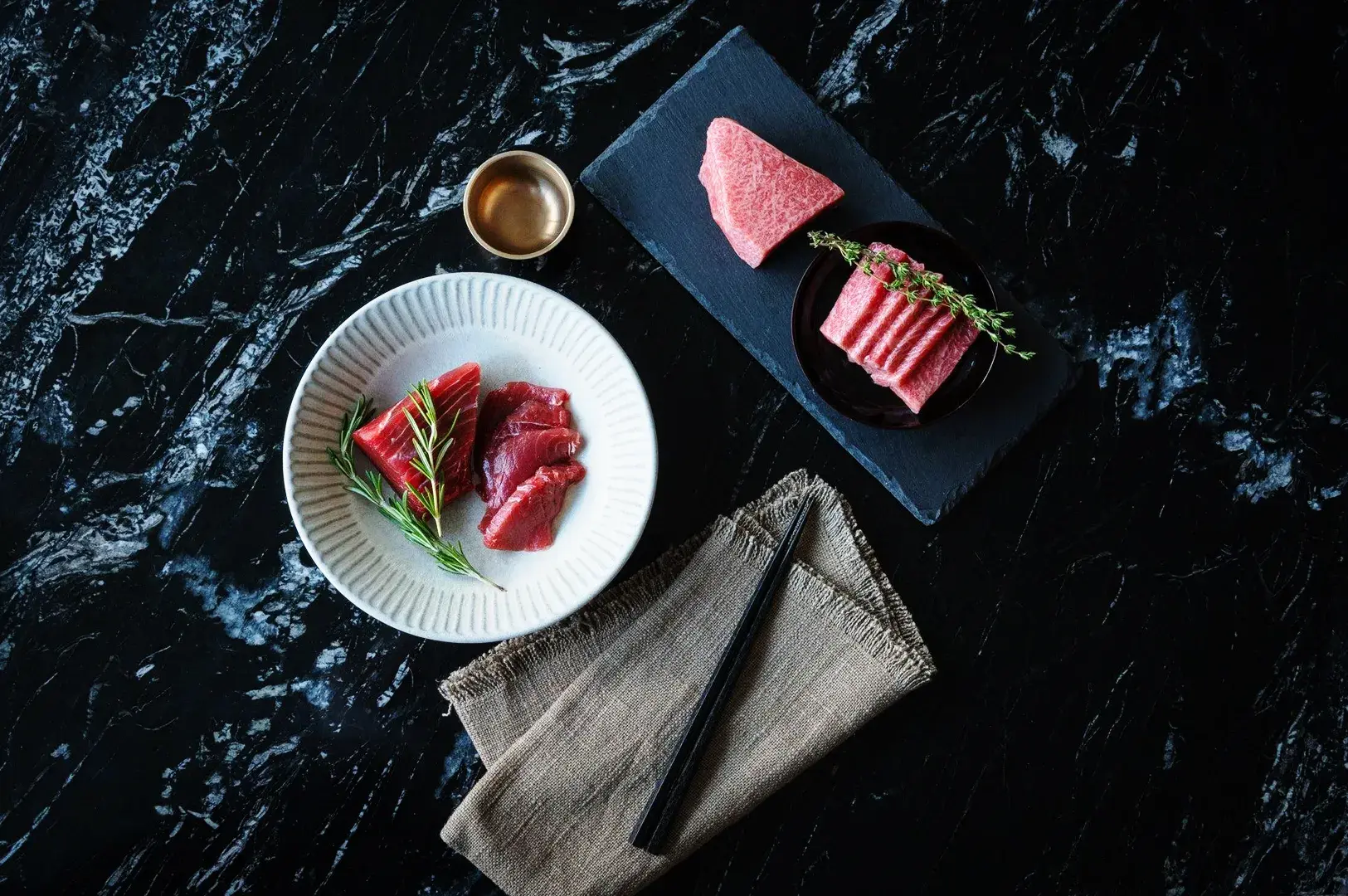 Premium raw tuna cuts prepared for sushi and sashimi on a dark presentation plate