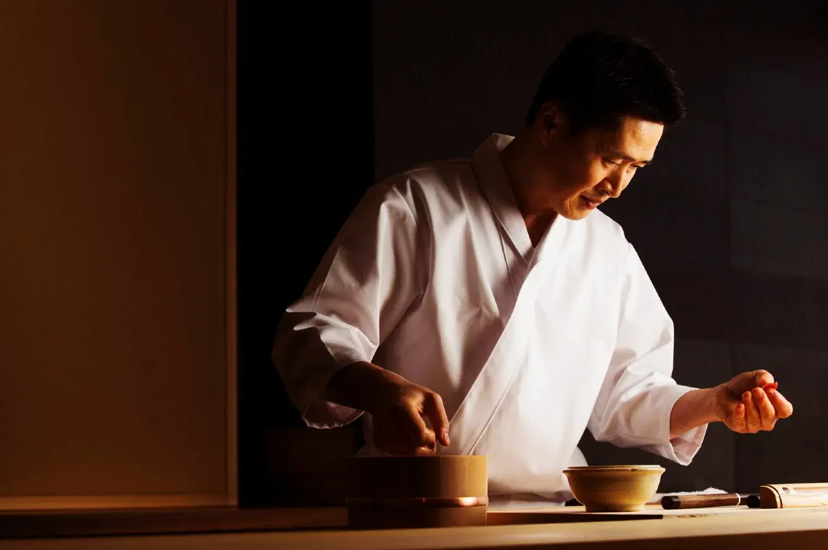Japanese sushi chef carefully preparing nigiri with precision and technique, representing traditional sushi craftsmanship and authentic Japanese cuisine