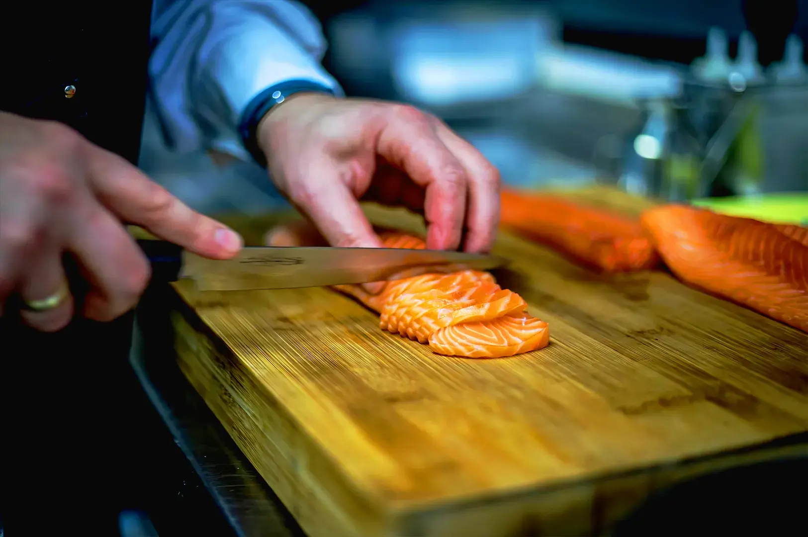 Japanese chef slicing fresh salmon sashimi with precision on a wooden board, representing authentic sushi preparation and Japanese culinary craftsmanship