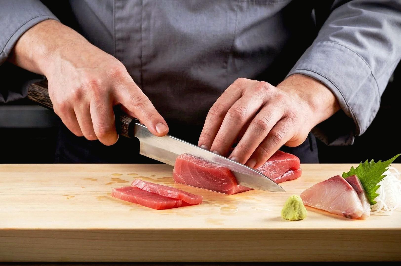 Japanese chef slicing fresh tuna sashimi with traditional knife preparation for premium sushi restaurants in Singapore