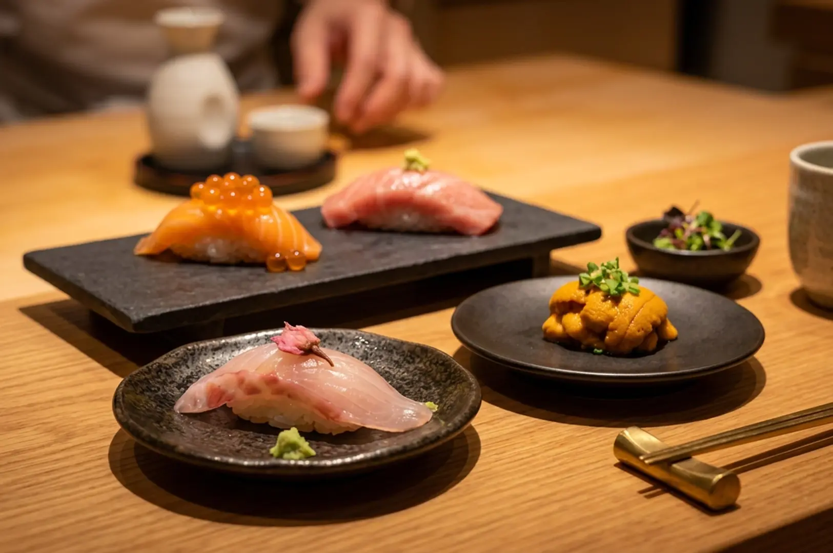 Seasonal omakase dishes elegantly plated on dark ceramic plates arranged on wooden counter with warm atmospheric lighting