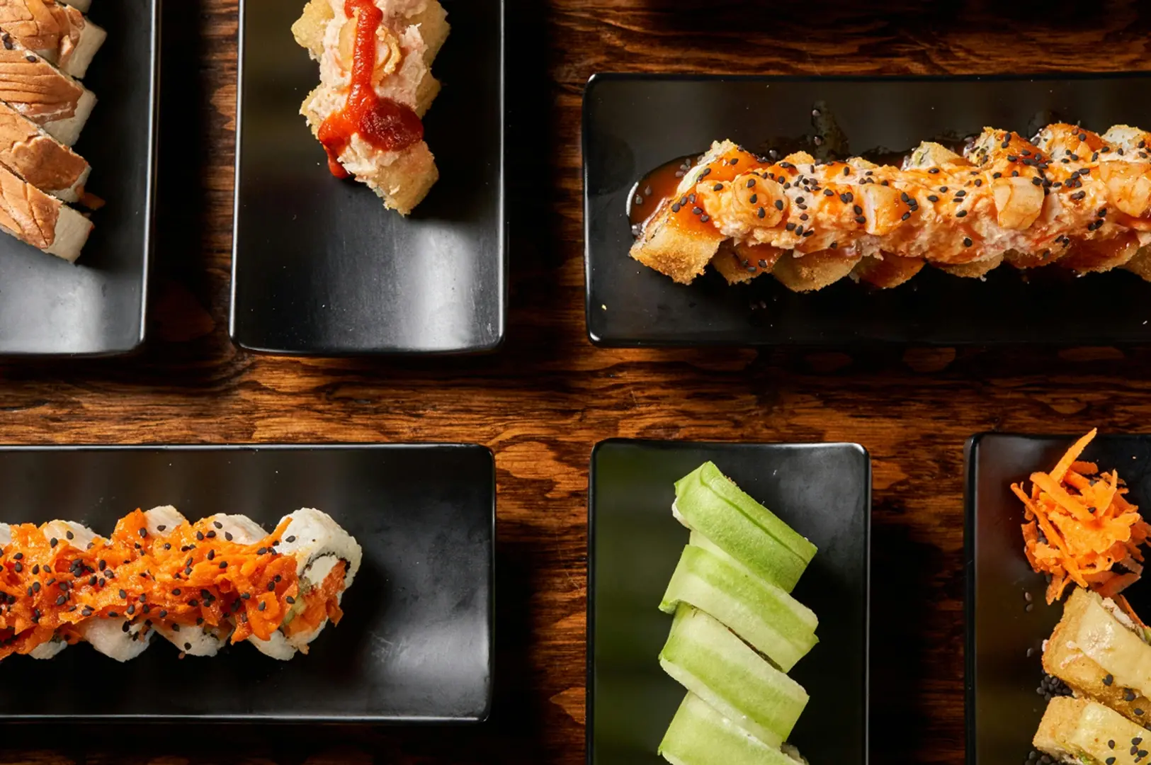 Side-by-side view of round Temari sushi on a blue plate and a salmon-filled Temaki hand roll on a slate platter.