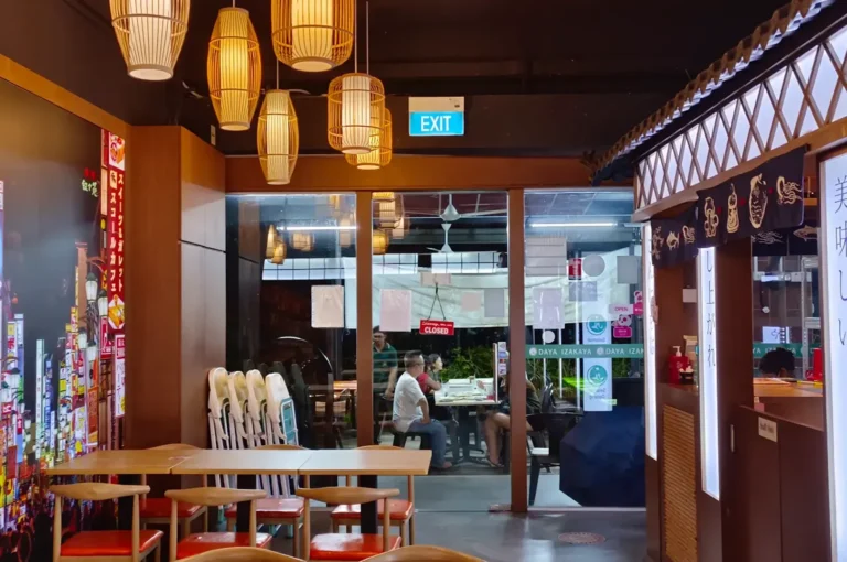 Daya Izakaya interior with warm lantern lighting, wooden tables, and a view toward the entrance.