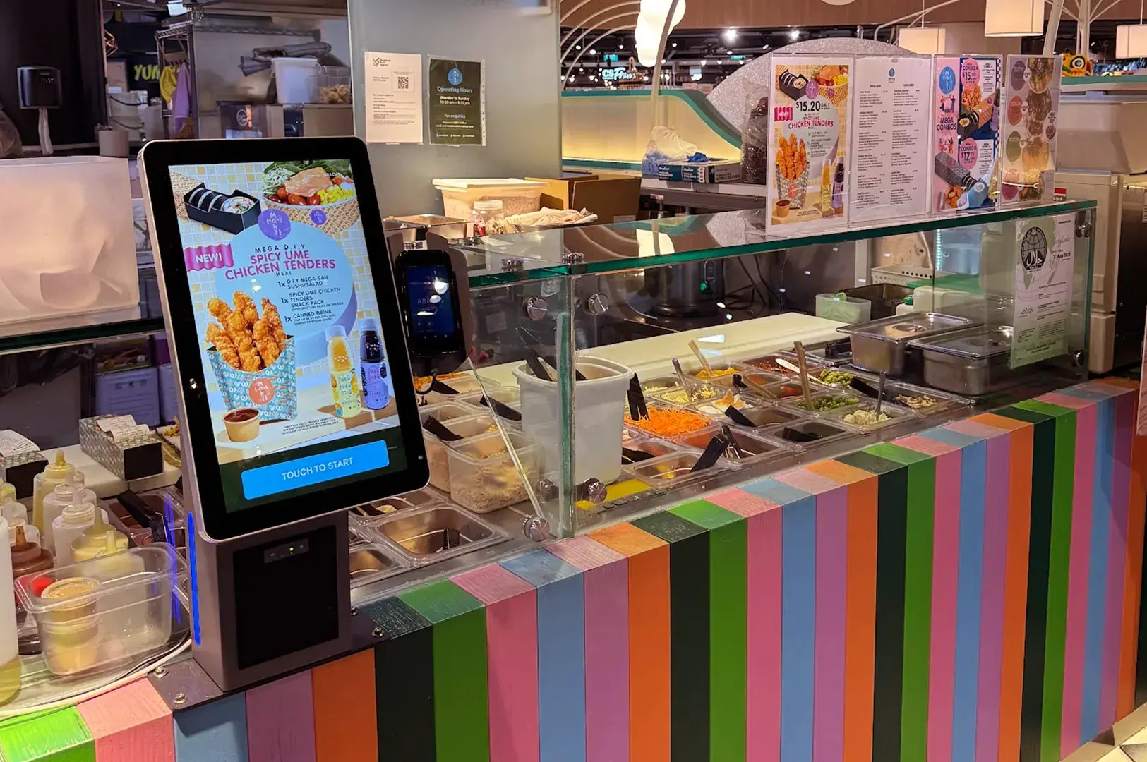 A restaurant counter with a touchscreen menu and ingredients behind a glass case.