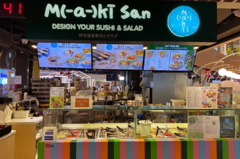 A Maki-San storefront counter with a lit sign and menu boards above.