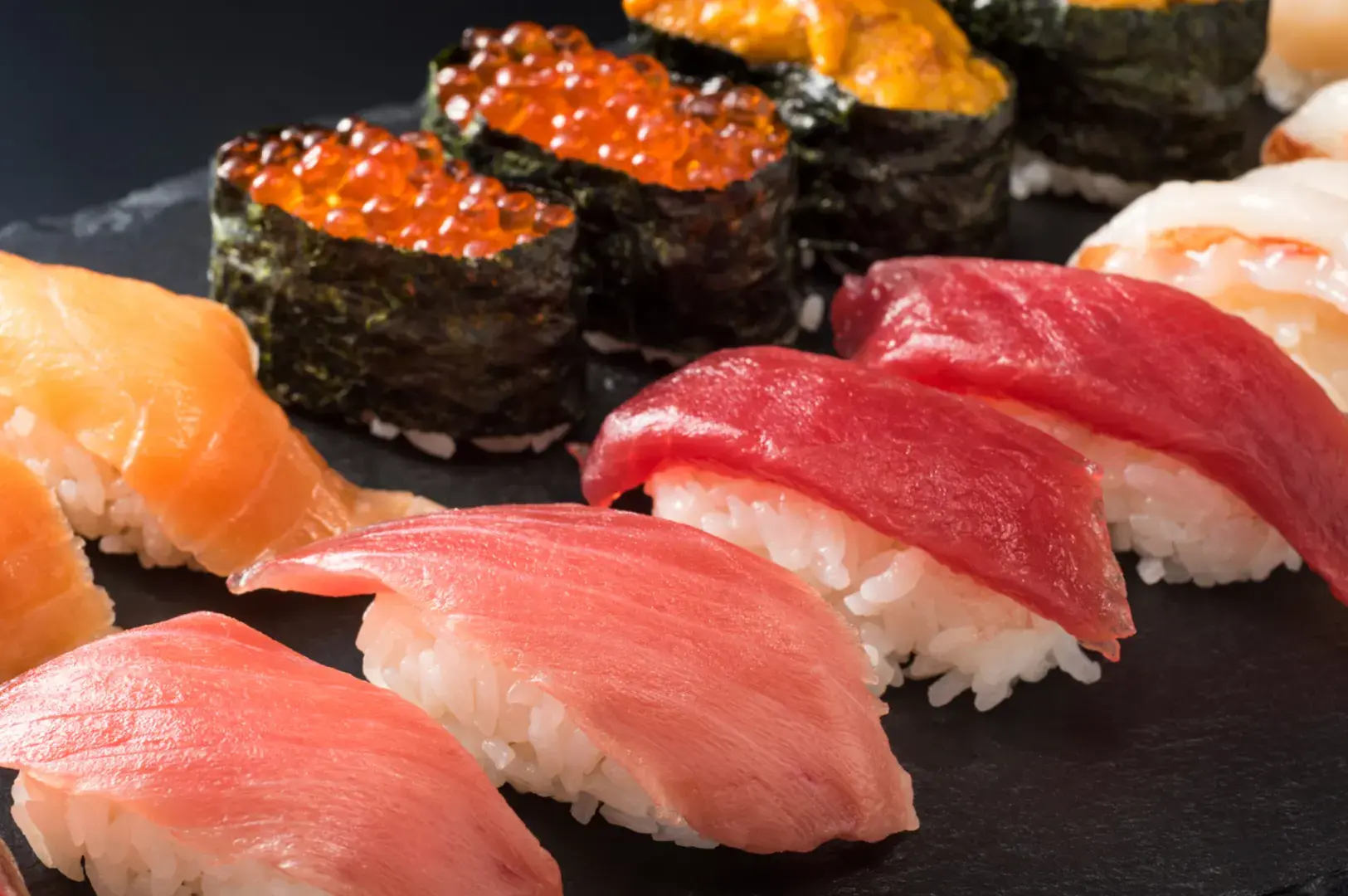 Assorted nigiri and gunkan on black plate