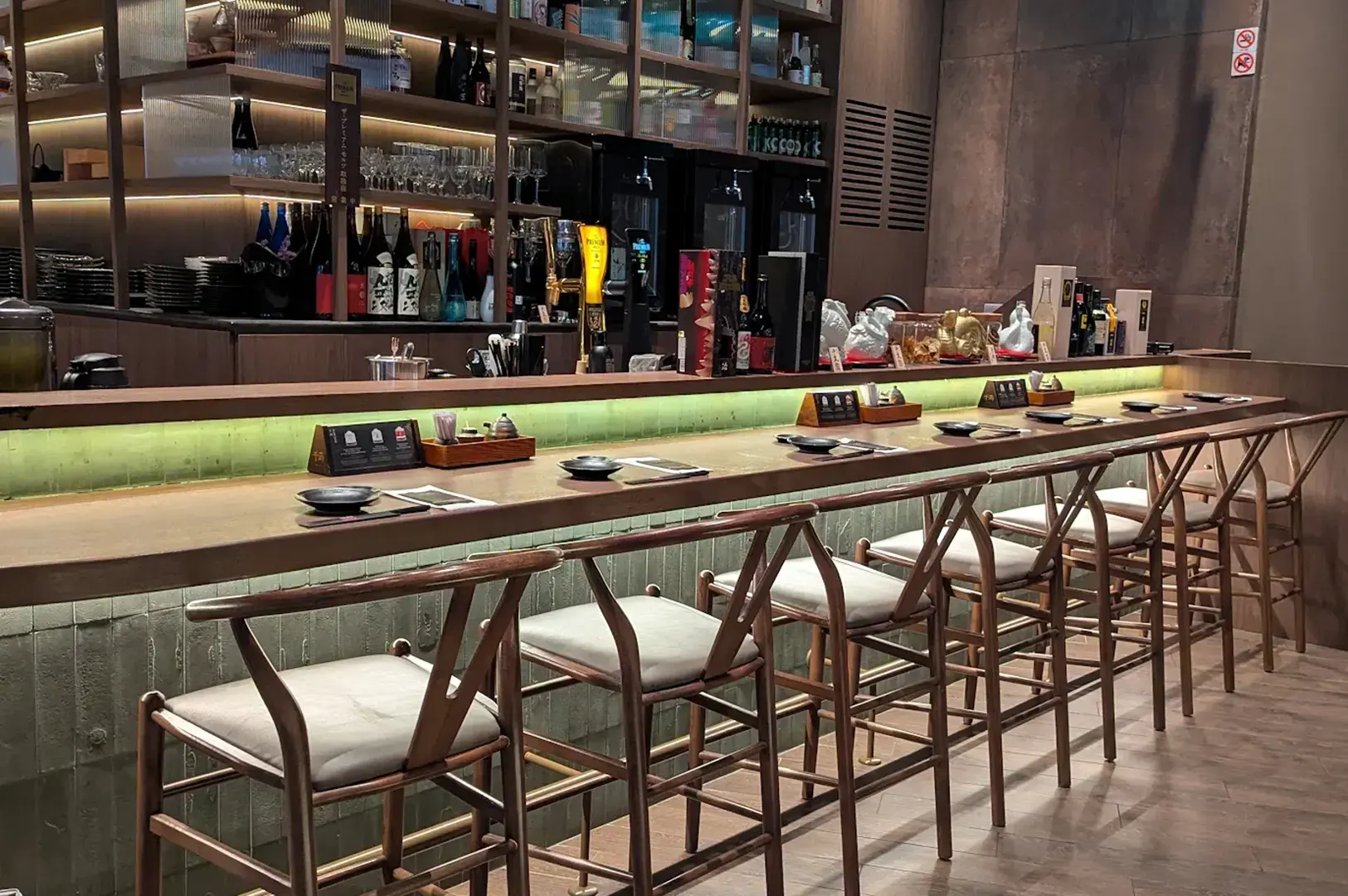 Sen-ryo sushi counter with plated dishes and backlit shelving.