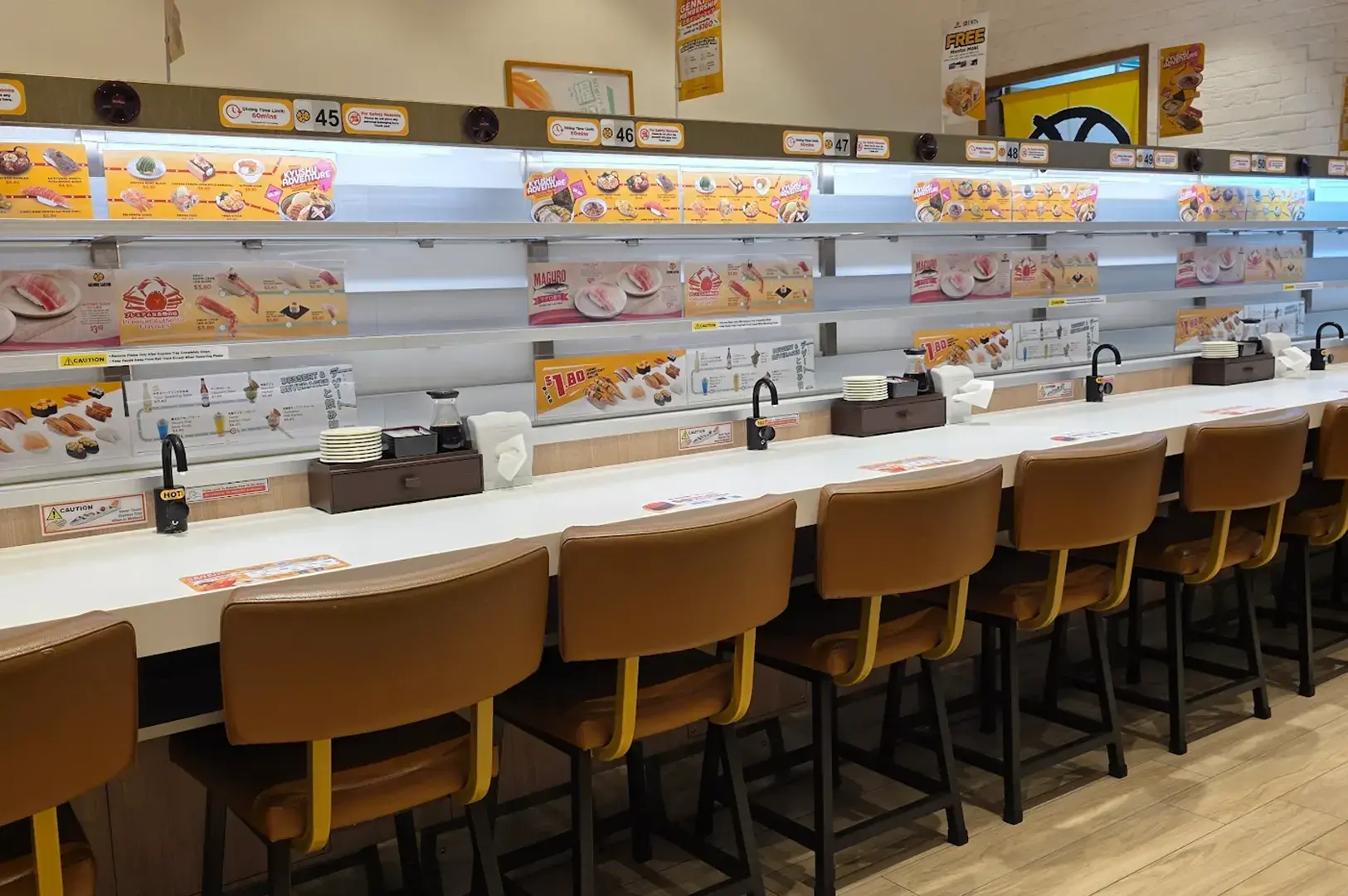 Genki Sushi interior with conveyor belt counter and yellow seating