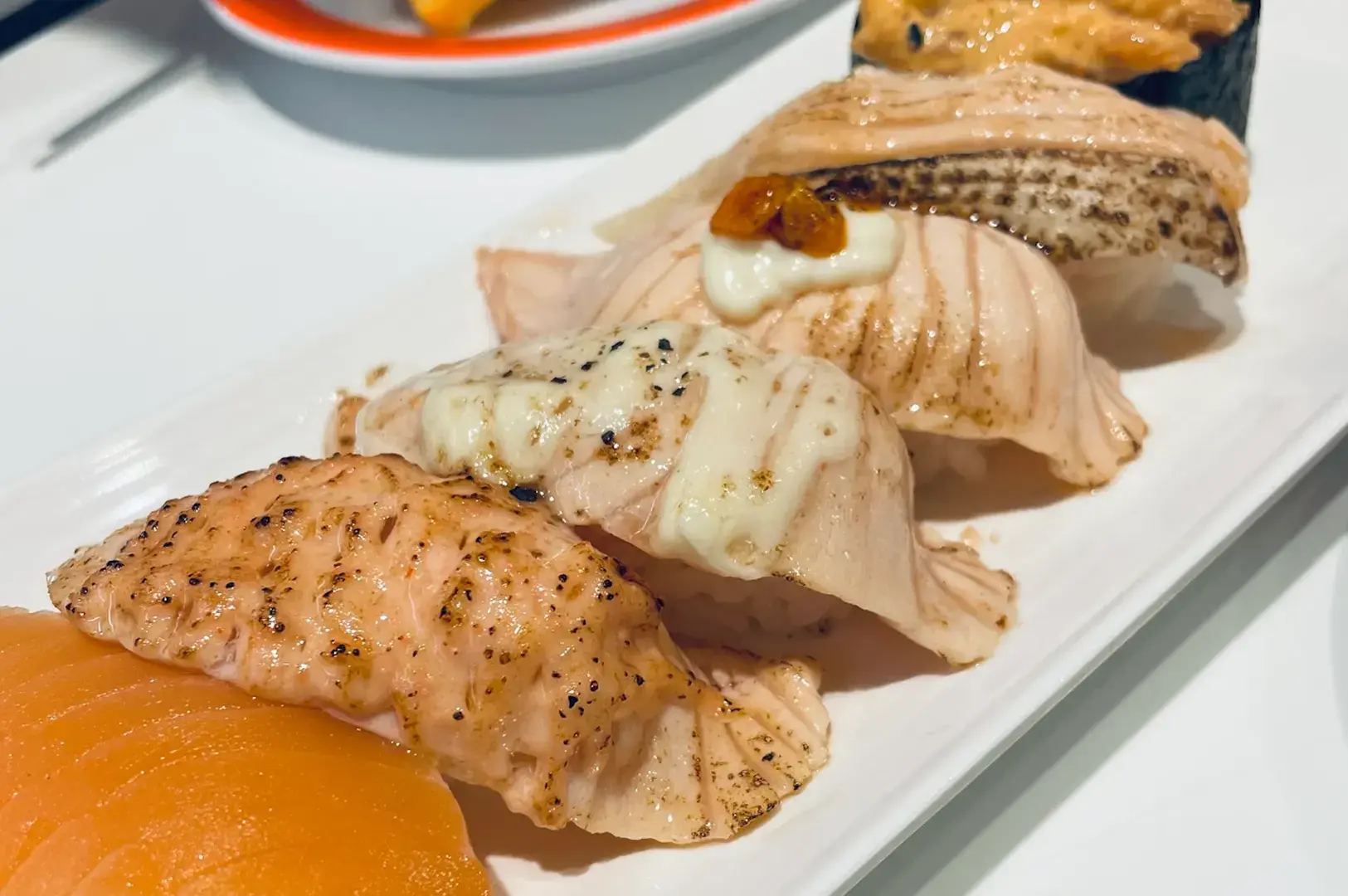 Aburi nigiri sushi platter with torched fish on white plate