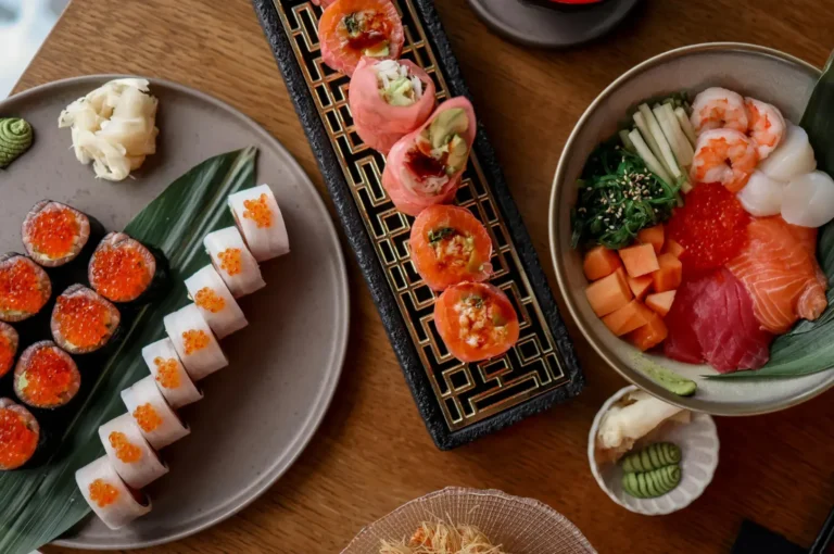 Assorted sushi nigiri, salmon aburi rolls, and chirashi bowl with sashimi on wooden table