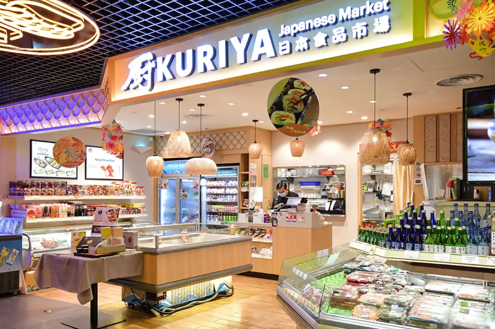 Bright Kuriya Japanese Market storefront with refrigerated displays, sake bottles, groceries, and staff behind the counter.