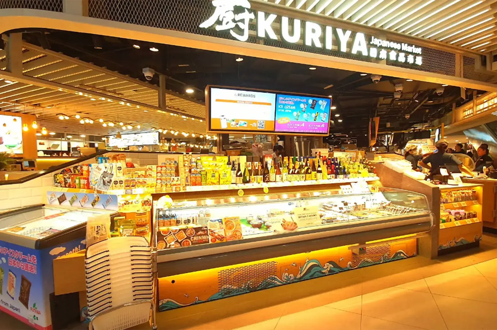 Kuriya Japanese Market counter displaying chilled seafood, sushi, Japanese groceries, and bottled beverages.