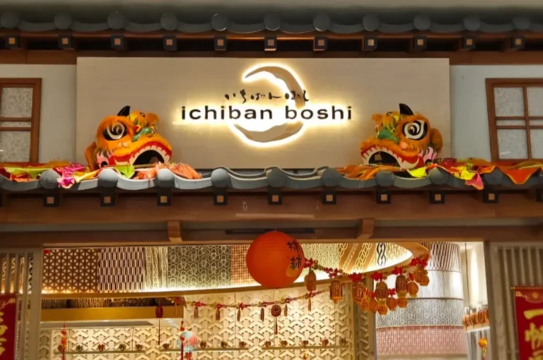 Illuminated Ichiban Boshi restaurant sign framed by traditional roof tiles, colourful lion dance decorations, red lanterns, and patterned Japanese-inspired interiors.