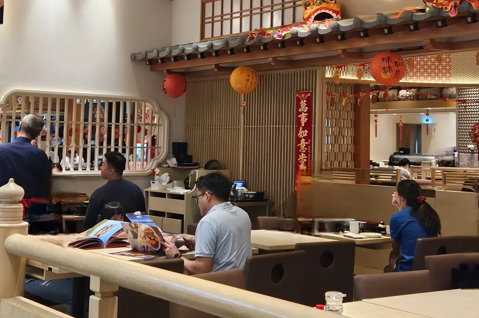 Diners seated at tables inside Ichiban Boshi, with Japanese decorations, hanging lanterns, wooden partitions, and a warmly lit restaurant interior.