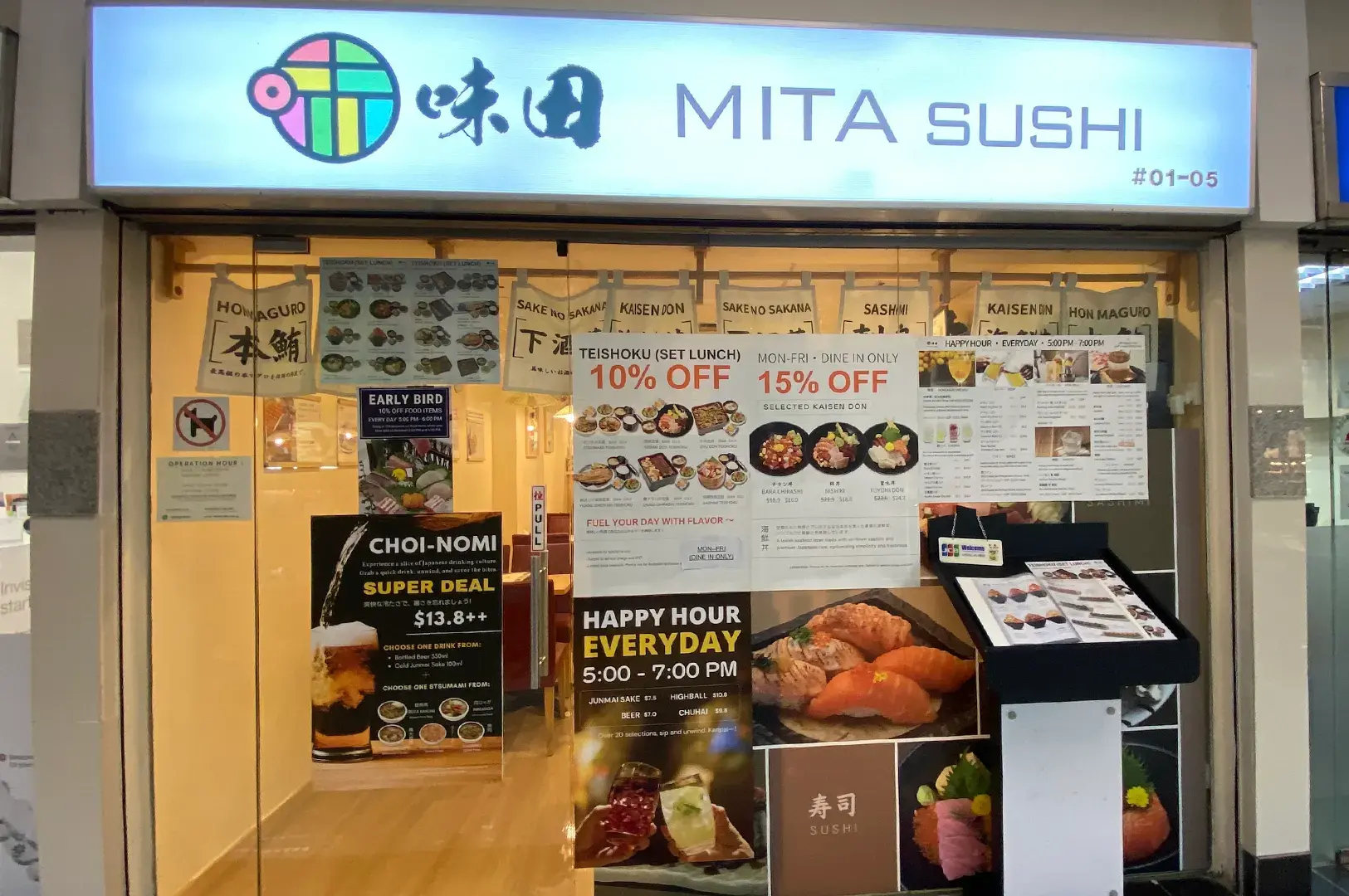 Exterior storefront facade of Mita Sushi Japanese restaurant showing promotional signs, banners, and menu displays.